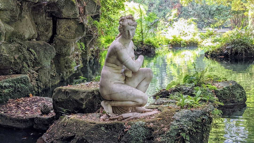 a statue sitting on top of a rock next to a body of water